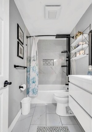 Een moderne badkamer met een douche, toilet en witte kastjes.