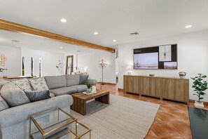 Ein modernes Wohnzimmer mit einem grauen Sofa, einem Holztisch und einem an der Wand befestigten Fernseher.