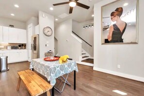 Una cocina moderna con armarios blancos, una mesa de comedor con mantel estampado y un banco de madera.