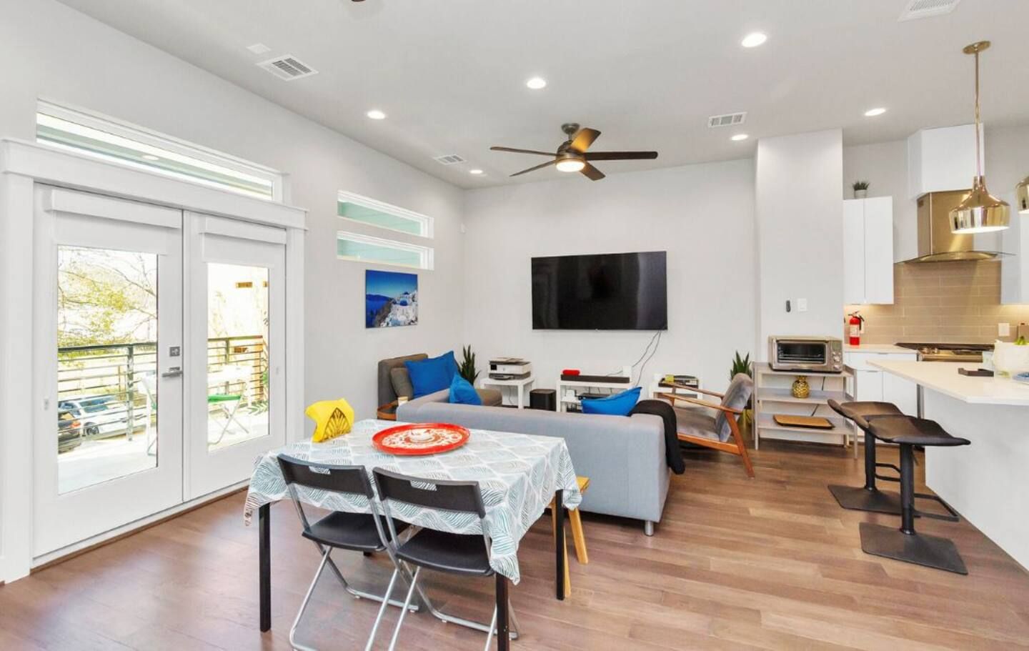 A modern living room with a sofa, TV, and dining area with chairs and a table.