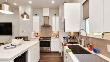 A modern kitchen with white cabinetry, stainless steel appliances, and pendant lighting.