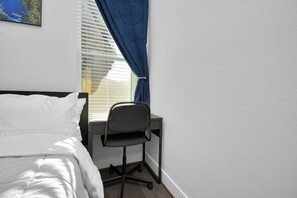 Un dormitorio con cama, escritorio y silla.