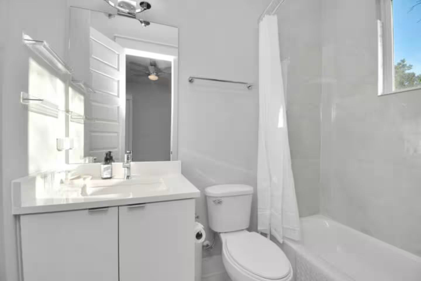 A modern bathroom with a white vanity, toilet, and bathtub.