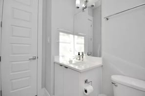 A modern bathroom with a white sink, a toilet, and a mirror. - Tx Home Group in Houston (Houston)