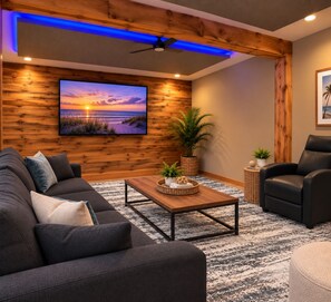 Un salon moderne doté d’un grand téléviseur à écran plat, d’un ventilateur de plafond et d’un mur décoratif en bois.