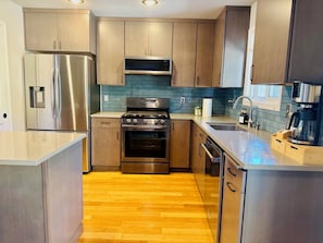 A modern kitchen with stainless steel appliances, wooden cabinets, and a blue backsplash. - Syringa House - 3 beds/2.5 baths Boise Retreat near Bown Crossing (Boise)