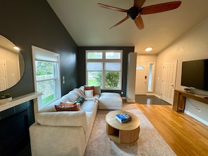 A modern living room with a sectional sofa, a round coffee table, a ceiling fan, and a television. - Syringa House - 3 beds/2.5 baths Boise Retreat near Bown Crossing (Boise)