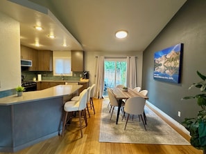 A modern kitchen with a central island, dining area with chairs, and a view of a natural landscape. - Syringa House - 3 beds/2.5 baths Boise Retreat near Bown Crossing (Boise)