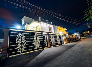 Una casa moderna de dos pisos con entrada porticada, un balcón e iluminación frontal destacada.