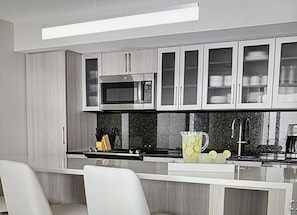A modern kitchen with a microwave, cabinets, a sink, and a bar area. - Stunning 2-bedroom villa in Marco Island with many pools, gym, island views. (Marco Island)