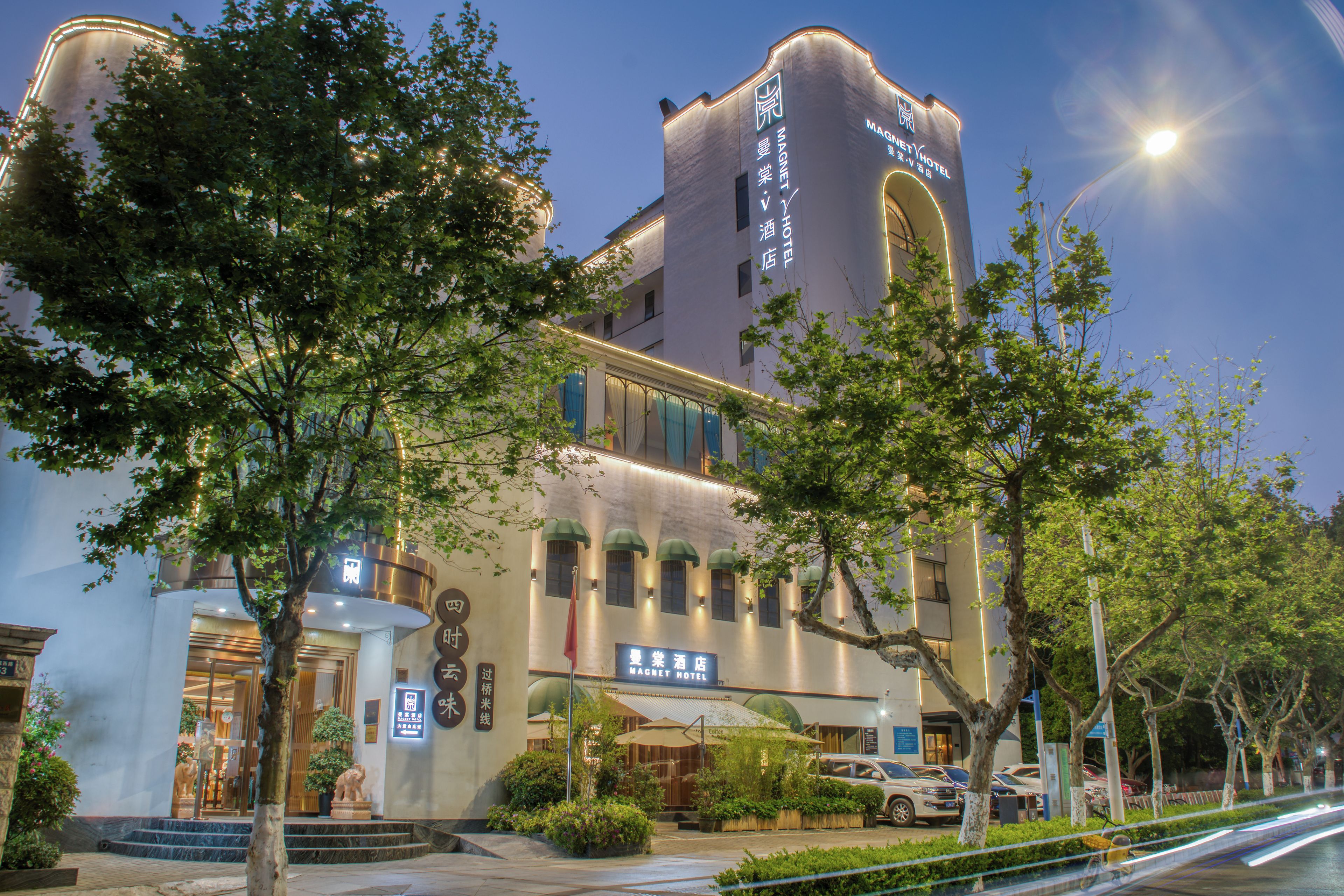 A hotel with a tower-like structure, a covered entrance, and a parking lot.