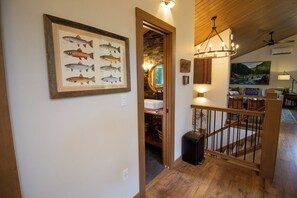 A staircase with a wooden railing leading to a second floor. A framed fish illustration is mounted on the wall above the staircase. - Roaring River Lodge - Riverfront, Fire Pit, EV (Rhododendron)