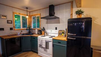 A compact kitchen with a stove, sink, and black refrigerator.