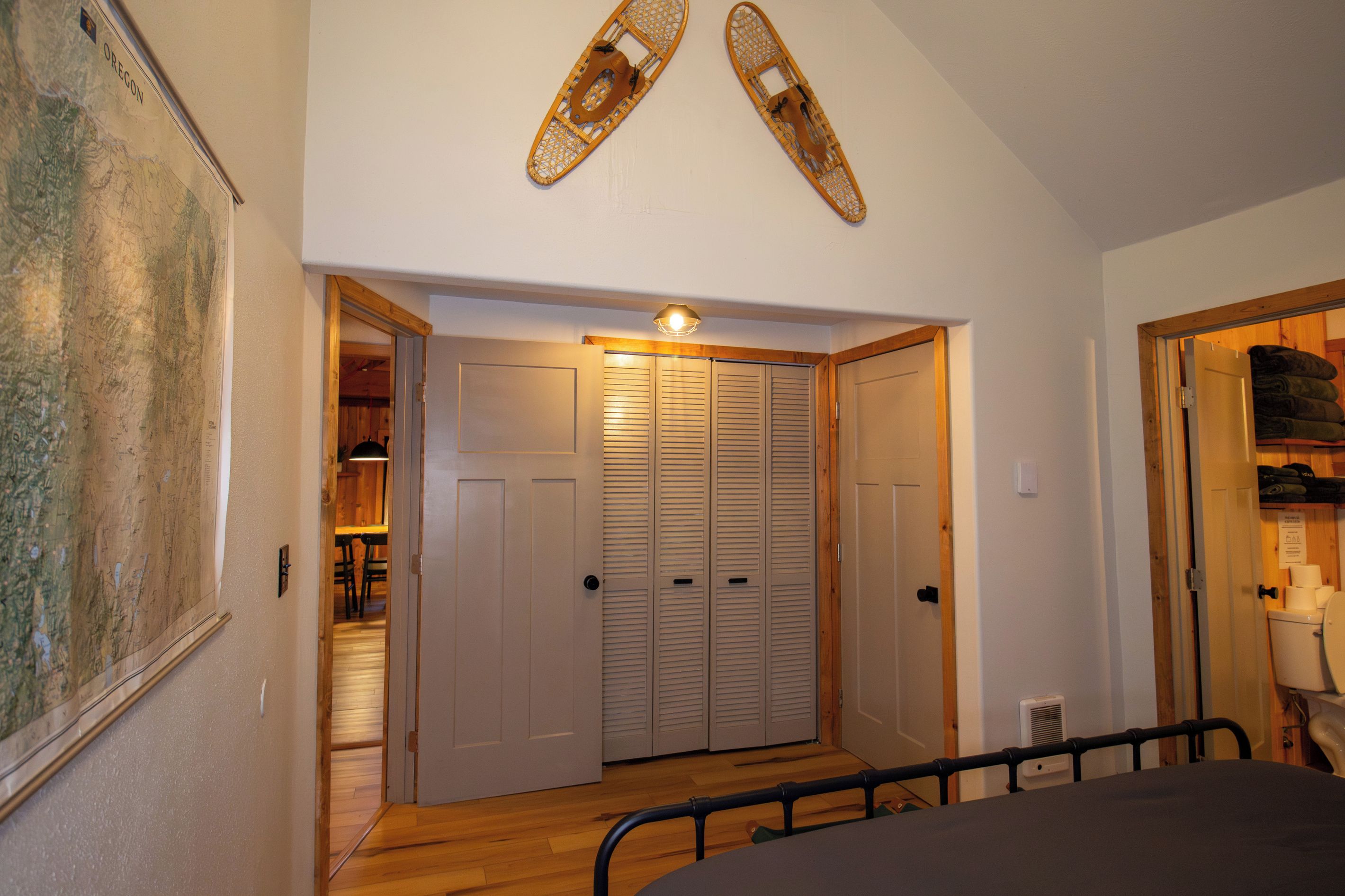 Une pièce comprenant un lit, un plancher en bois, un placard avec des portes coulissantes et une étagère fixée au mur.