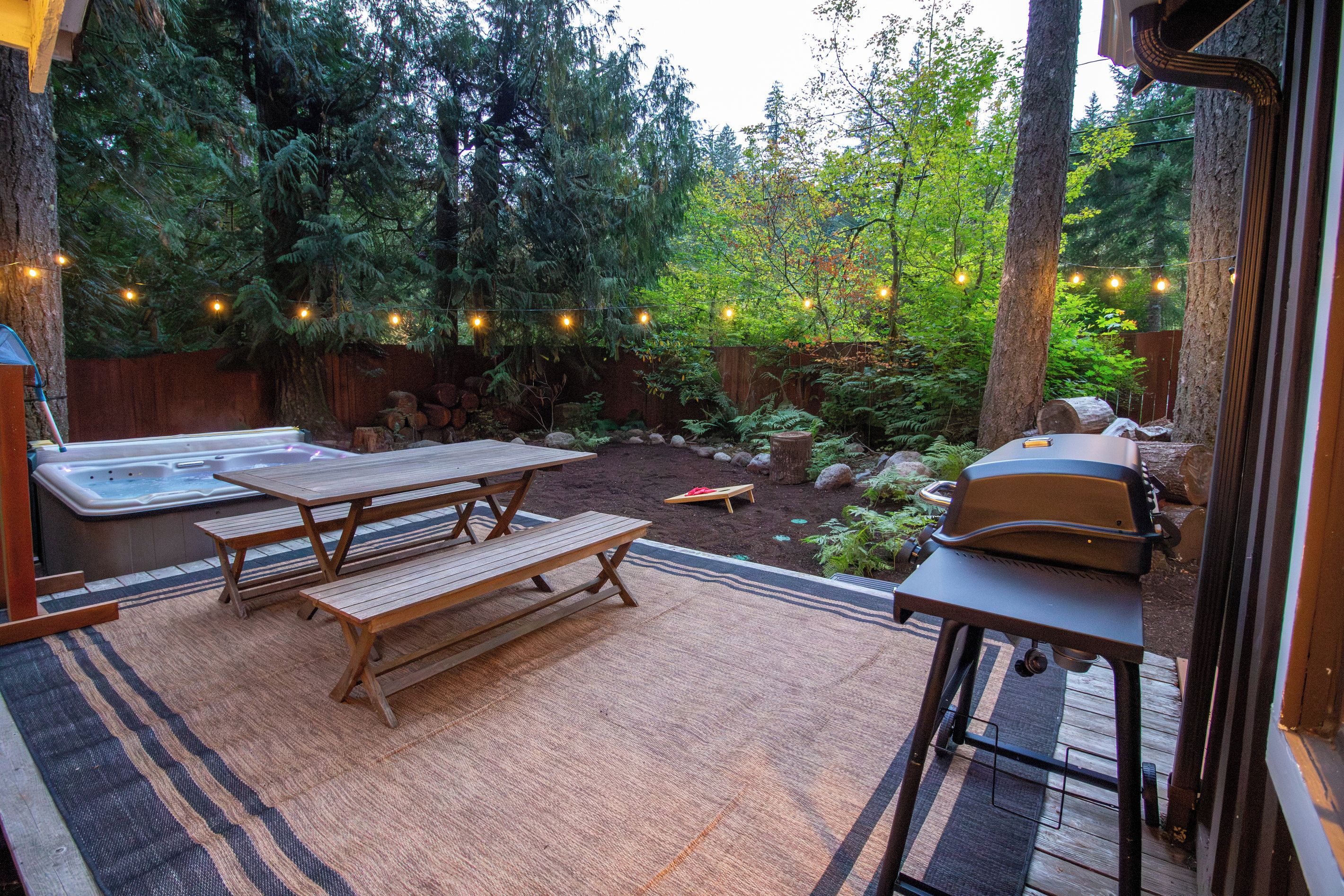 Ein Außenbereich mit Terrasse, Whirlpool, Picknicktisch und Grill.