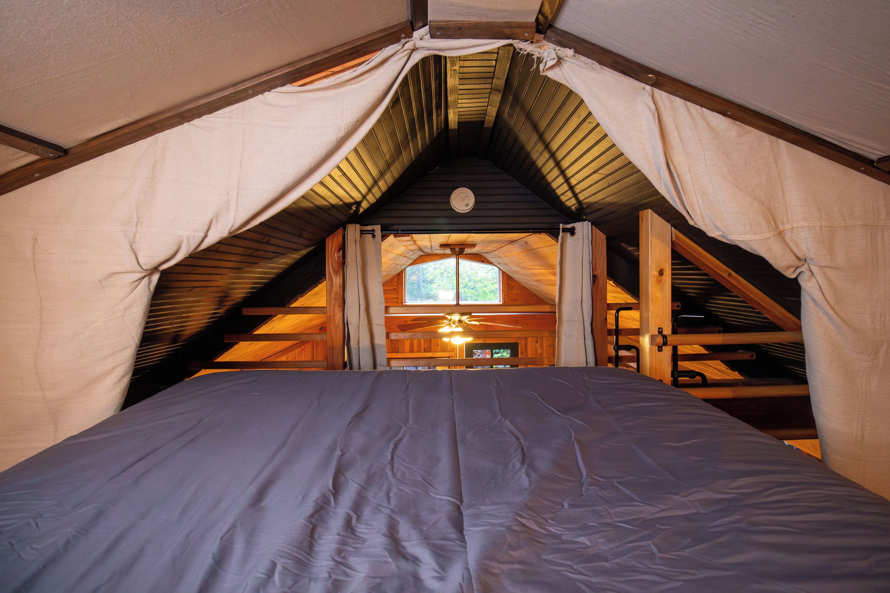 Un dormitorio con cama, ventana y ventilador de techo.