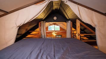 Un dormitorio con cama, ventana y ventilador de techo.