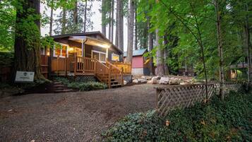 A lodge with a wooden deck, a covered porch, and a gravel driveway.