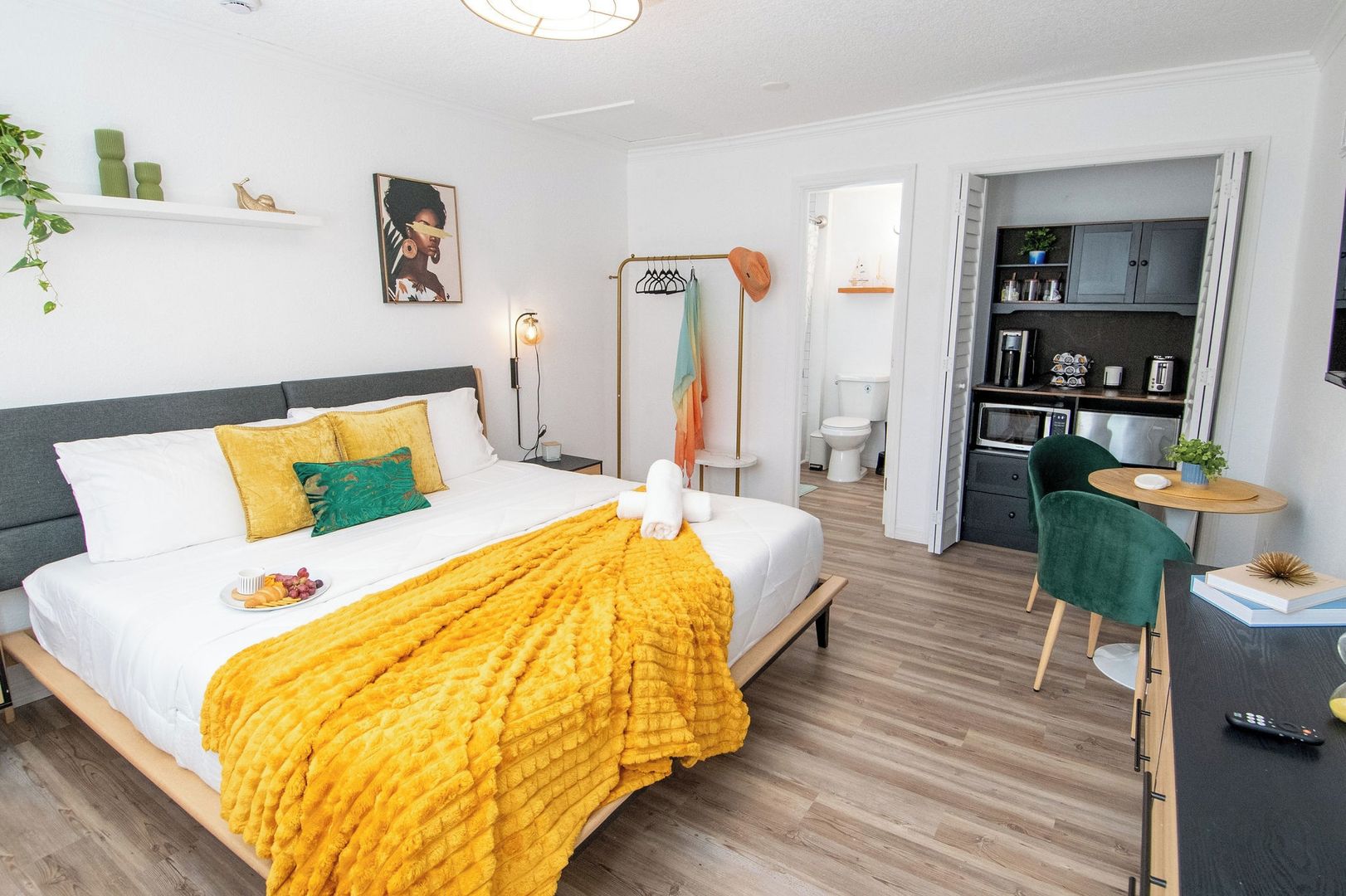 Ein modernes Hotelzimmer mit Bett, Nachttisch und Blick in den Küchenbereich.