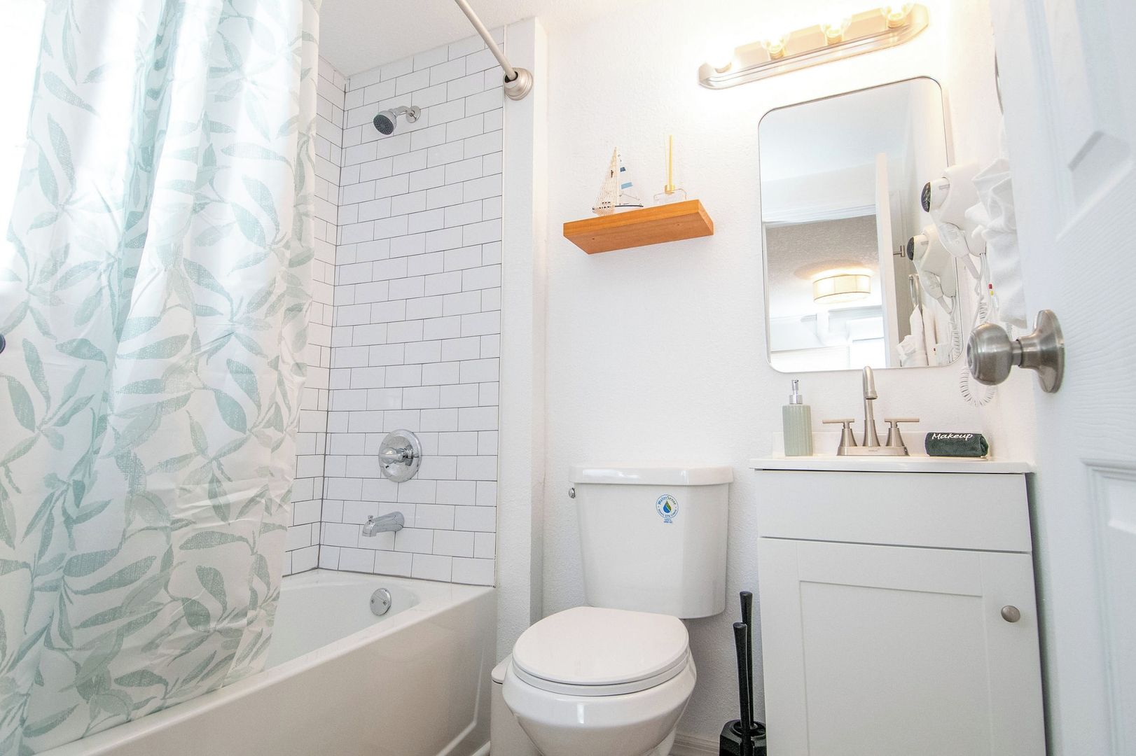 Ein Badezimmer mit Dusche, Toilette und Waschtisch mit Spiegel.