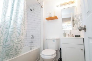 Un baño con ducha, inodoro y tocador con espejo.