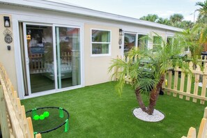 Propiedad residencial con patio, césped artificial, valla de madera y una palmera.