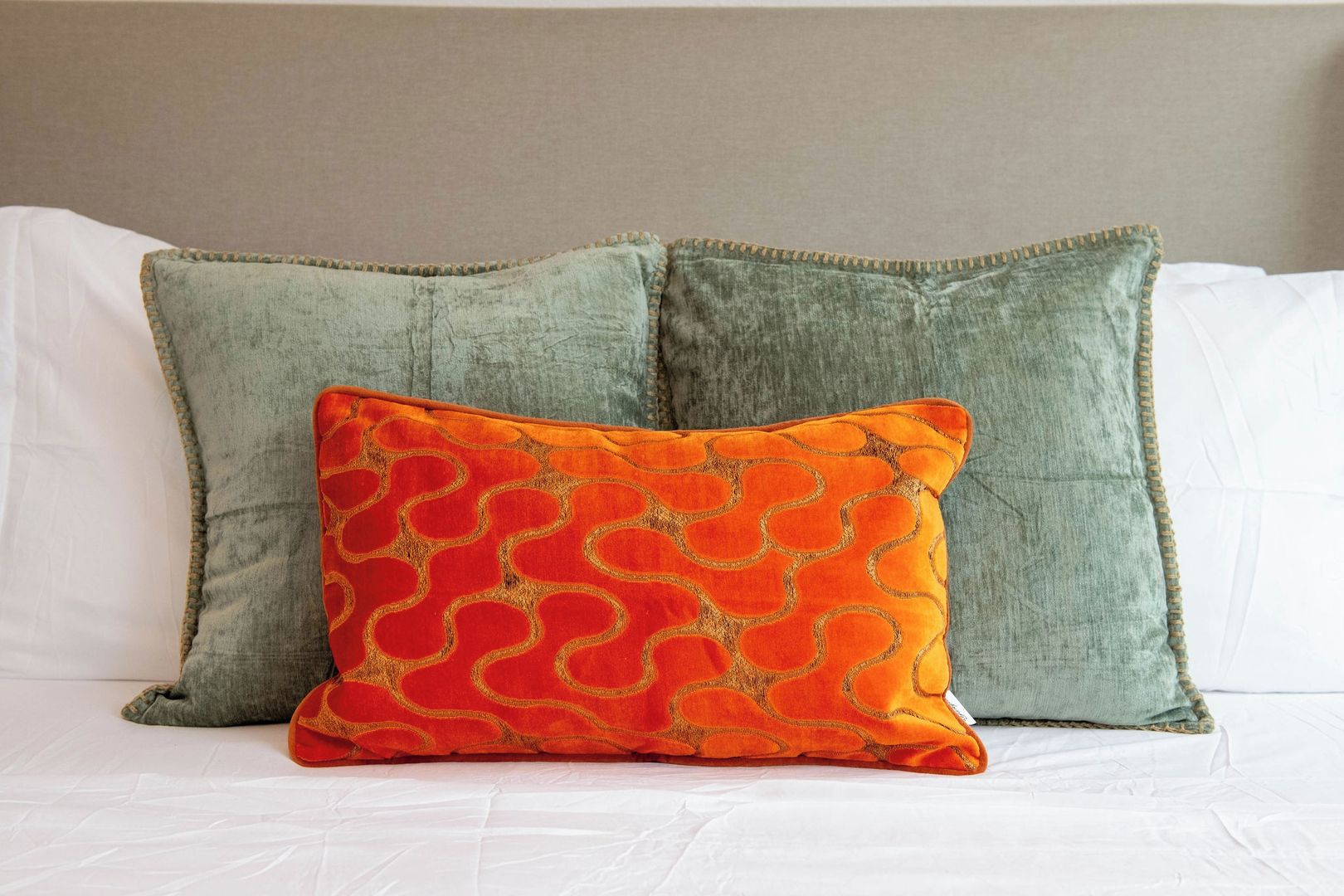 A bed with two pillows, one plain and one patterned.