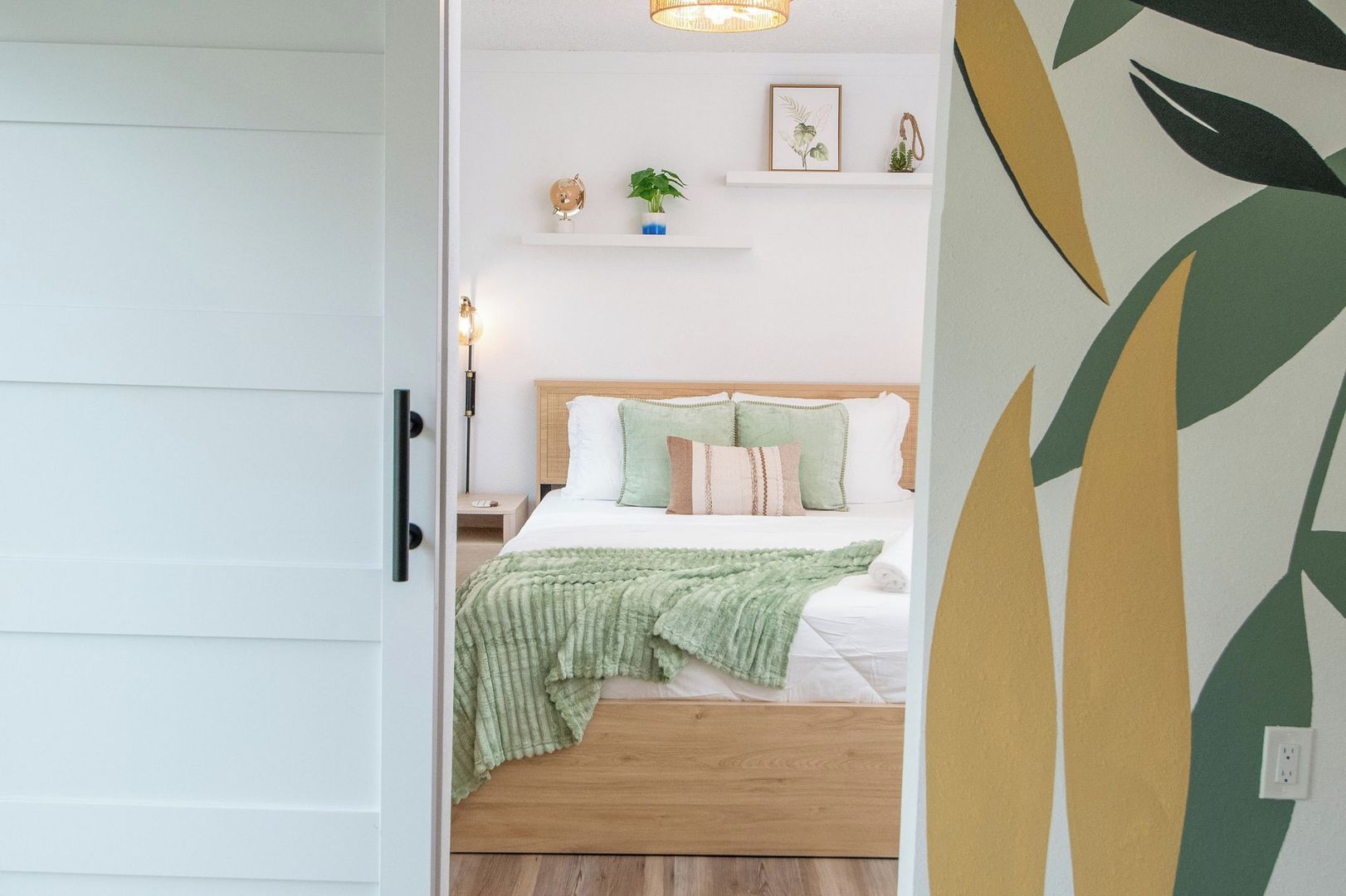 Un dormitorio con cama, mesita de noche, lámpara y decoración en la pared.