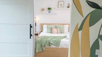 Un dormitorio con cama, mesita de noche, lámpara y decoración en la pared.