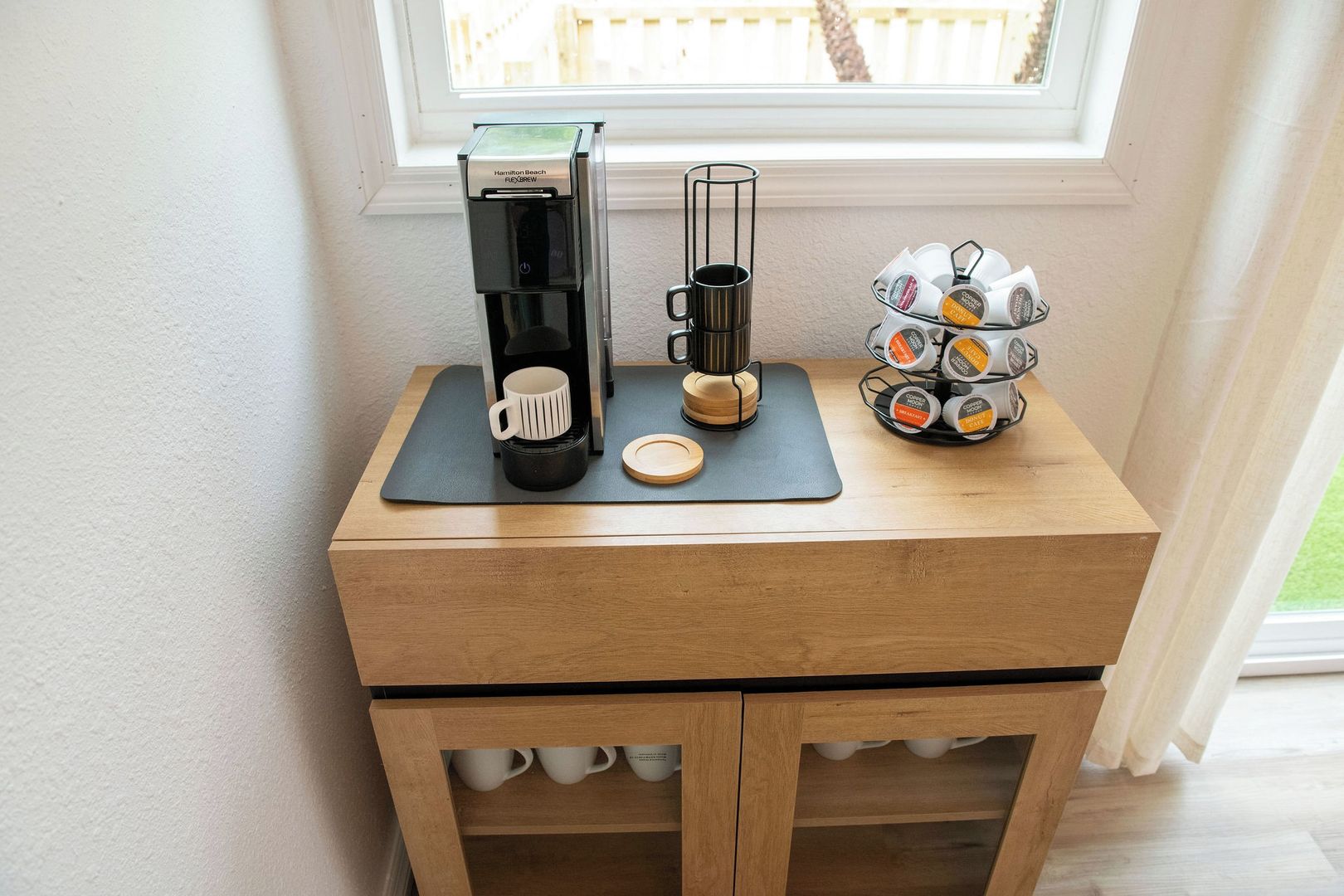 Eine Kaffeestation mit einer Hamilton Beach Kaffeemaschine, einem Kaffeekännchen, einer Tasse und einem Kaffee-Pad-Halter.