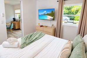 Une chambre d’hôtel avec un lit, un bureau, une télévision et une vue sur la plage.