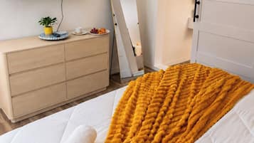 Un dormitorio con cama, televisor, cómoda, espejo y puerta corredera.