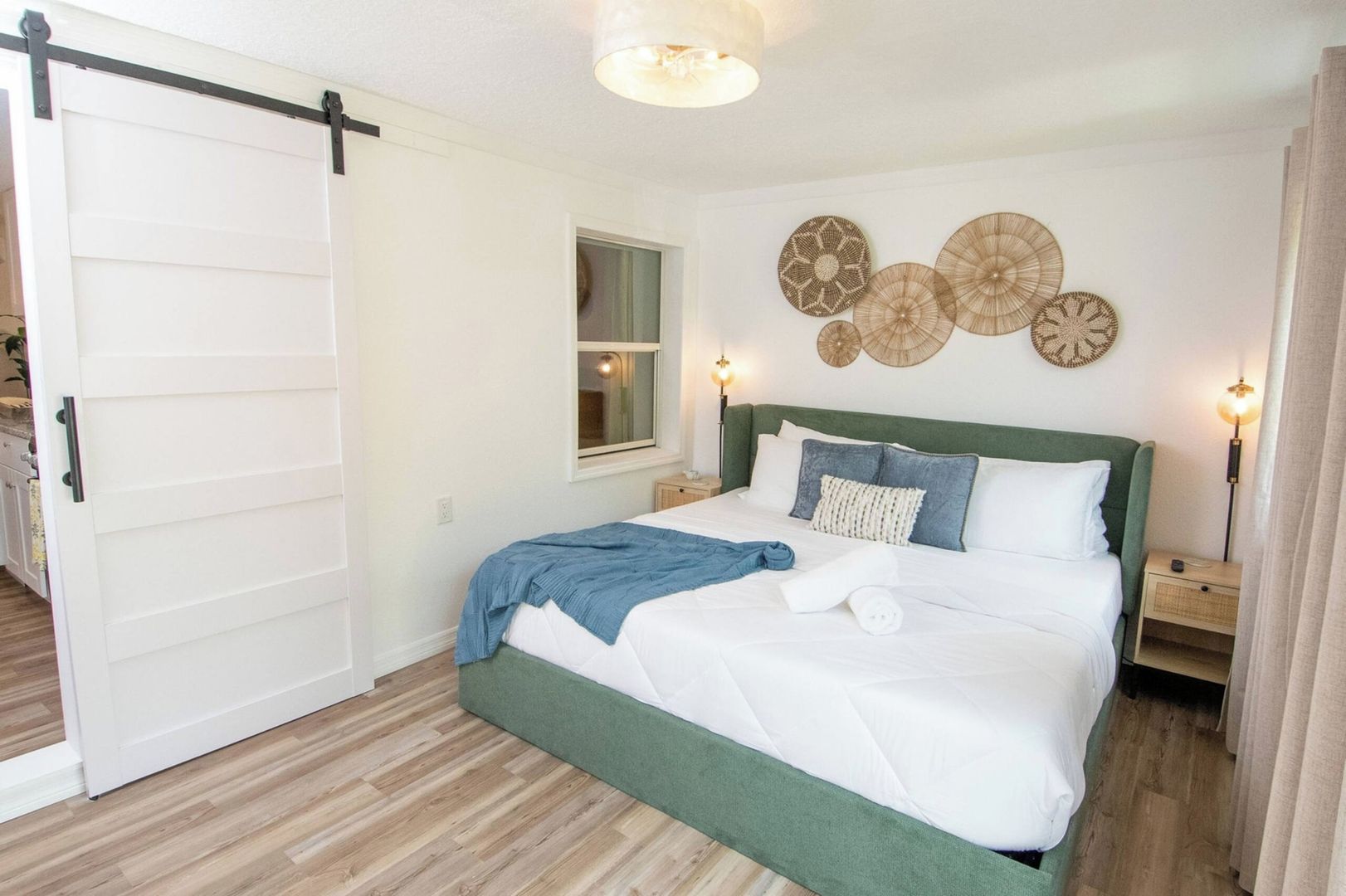 Une chambre à coucher avec un lit, une fenêtre, des éléments de décoration murale et une porte coulissante.