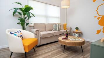 Ein Wohnzimmer mit einer Couch, einem Sessel, einem Couchtisch und einem Blumentopf.