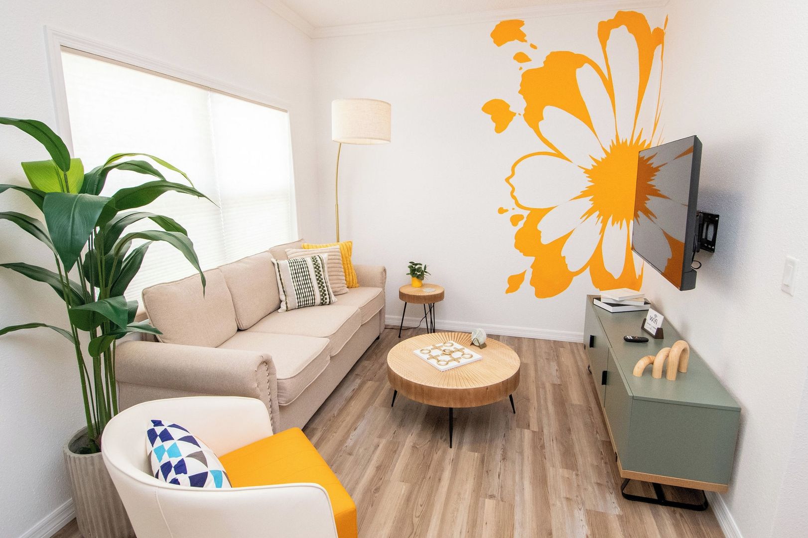 Un salon moderne avec un canapé, une table basse, un téléviseur et une grande plante.