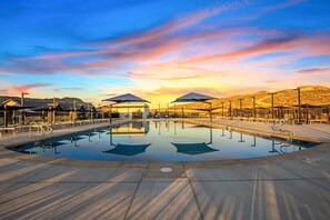 Ein Swimmingpool mit Sonnenuntergangsblick, schattigen Bereichen und einer Wüstenlandschaft im Hintergrund.