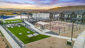 Zona residencial con casas, una cancha de tenis y un césped verde.