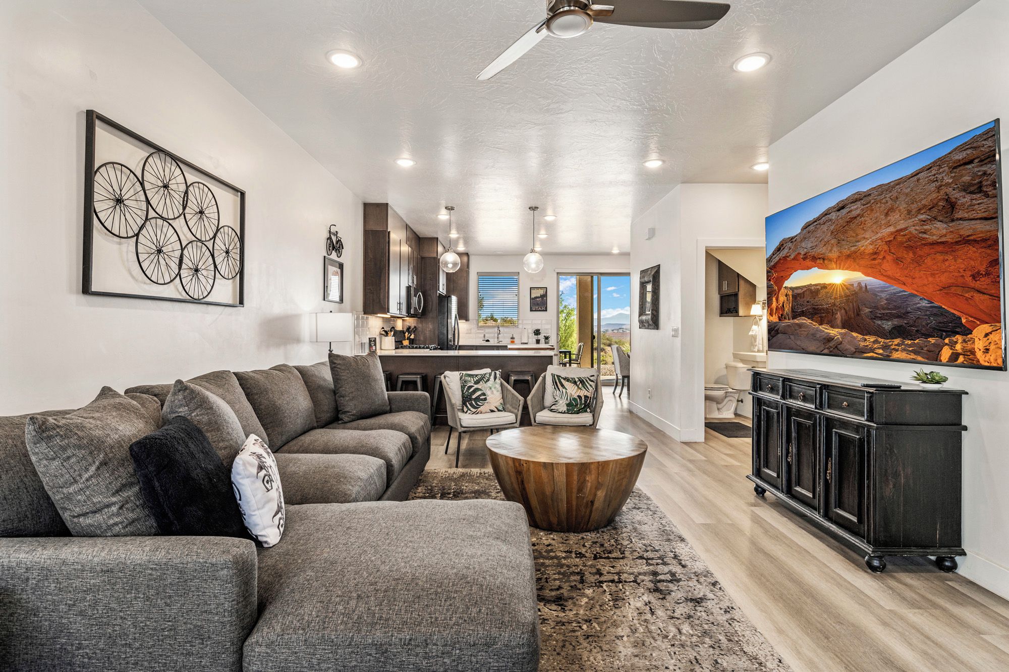 A modern living room with a sectional sofa, a coffee table, and a large painting of a canyon.