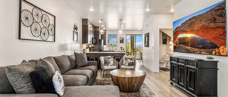 A modern living room with a sectional sofa, a coffee table, and a large painting of a canyon.