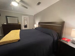 Une chambre d’hôtel avec un lit, une table de chevet, une lampe et une porte.