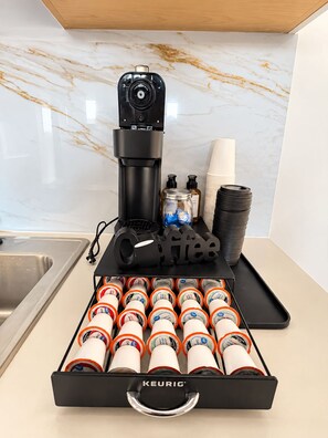 Ein Kaffee-Bereich mit einer Keurig-Maschine, Einwegbechern und einer Kaffeekapsel-Auswahl.