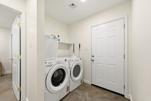 A laundry room with two Whirlpool washers, a drying rack, and a door. - Two Private Homes | 5 King Bedrooms | Sleeps 10 (Lafayette)