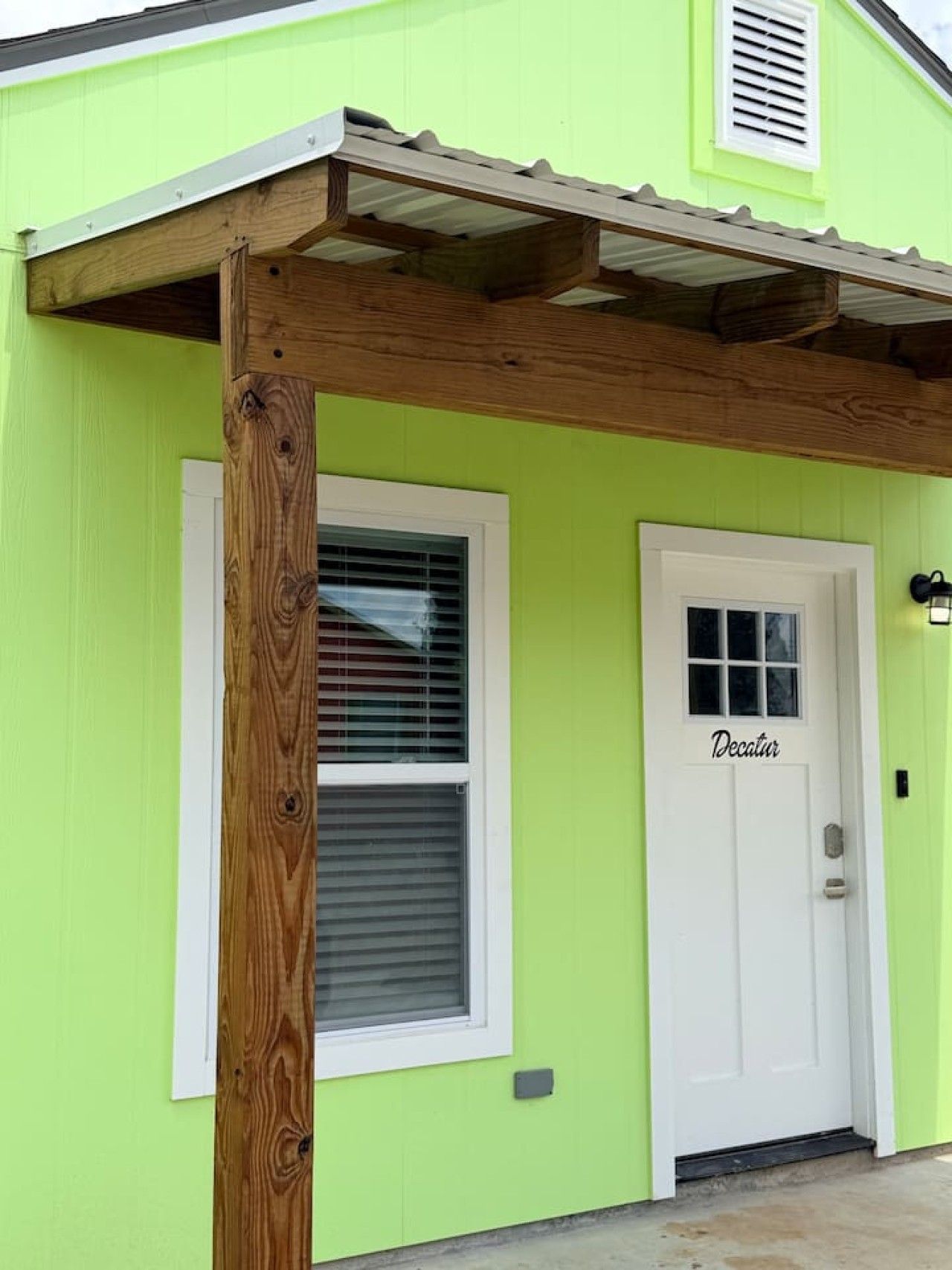 A building with a green exterior, a white door labeled 'Decatur,' and a wooden post.
