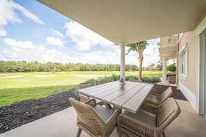A covered patio with a table and chairs, overlooking a golf course. - The Centre at Reunion-1356 (Kissimmee)