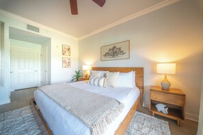 A bedroom with a large bed, bedside lamps, a nightstand, and a wall-mounted painting. - The Centre at Reunion-1356 (Kissimmee)