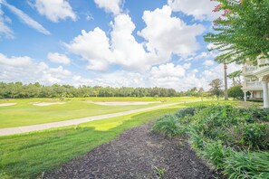 A golf course with a clear sky and a building with a balcony. - The Centre at Reunion-1356 (Kissimmee)