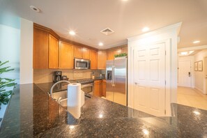 A modern kitchen with granite countertops, stainless steel appliances, and wooden cabinets. - The Centre at Reunion-1356 (Kissimmee)