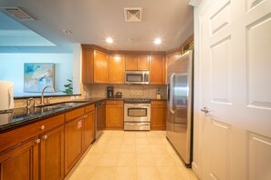 A modern kitchen with wooden cabinets, stainless steel appliances, and a tiled floor. - The Centre at Reunion-1356 (Kissimmee)
