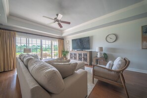 A living room with a sofa, a chair, a television, and a clock on the wall. - The Centre at Reunion-1356 (Kissimmee)