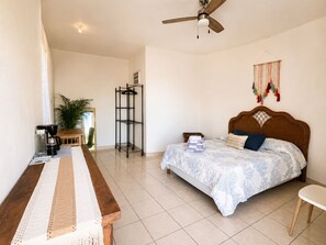 A bedroom with a bed, a desk, a coffee maker, a shelf, and a ceiling fan. - Best Ocean View and Pool (San José del Cabo)